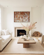 Under His Care, Isaiah 54:17 canvas print above a fireplace in a cream living room with spring blossom